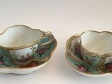 two cups and saucers are sitting on a white surface