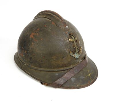 un vieux casque orné d'une ancre, posé sur une surface blanche