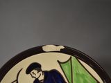 a ceramic plate with a picture of a man holding a green umbrella