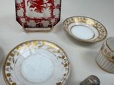 a white table with a red and gold plate and silverware