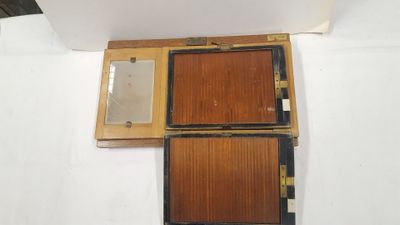 une vieille boîte en bois contenant un miroir, posée sur une surface blanche