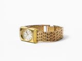 a gold wrist watch with a white face on a white surface