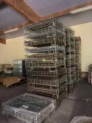 a large stack of cages in a warehouse with pallets and boxes