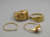 three gold rings and a pearl ring on a table
