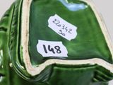 a green vase with a label on it on a table