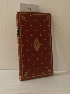 un livre rouge aux bords dorés posé sur une étagère blanche