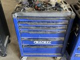 une boîte à outils bleue sur laquelle sont posés des outils, dans un garage