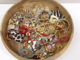 a wooden bowl filled with assorted jewelry on a table