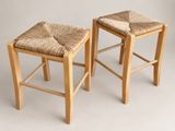 two wooden stools with woven seats against a white background