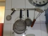 hanging pots and pans on a wall with a clock in the background