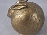 une pomme dorée surmontée d'une feuille