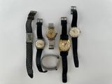 trois montres et un bracelet de montre sont posés sur une surface blanche