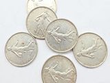 six coins of different sizes and shapes on a white surface