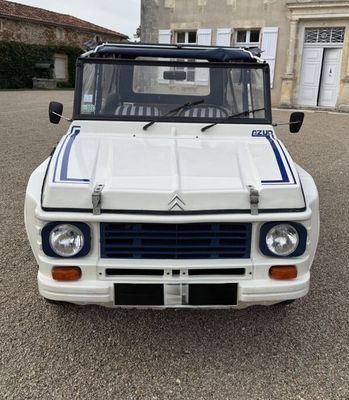 un camion blanc avec des bandes bleues garé devant un immeuble