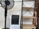 a room with a fan, a table, and other items on the floor