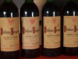 four bottles of red wine are lined up on a table
