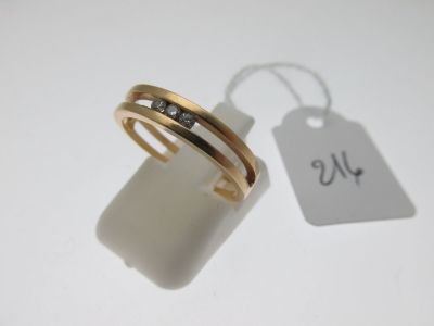 une bague en or sertie de deux diamants, à côté d'une étiquette de prix