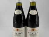 two bottles of red wine sitting next to each other on a white surface