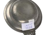 an old silver plate with a sticker on it sitting on a table