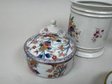 a white container with a flower design on it next to a white container with a flower design on it