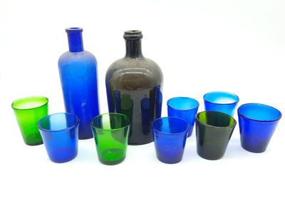 plusieurs verres de différentes couleurs et une bouteille sur la table