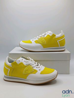 une paire de baskets jaunes et blanches posée sur une boîte