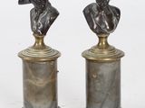 une paire de bustes en bronze représentant un homme et une femme, posés sur des socles