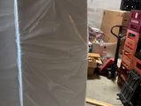 un grand matelas blanc posé sur une palette dans un entrepôt
