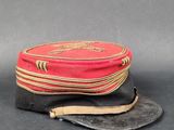 un vieux chapeau rouge orné d'un bandeau en cuir et d'une lanière marron