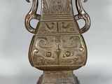 un vase en bronze posé sur un socle en bois