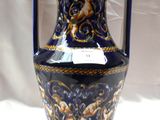 un vase bleu et doré posé sur une table blanche