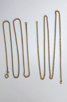 plusieurs types de colliers en or disposés sur une surface blanche