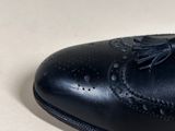 black leather shoes with tassels on a white surface