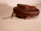 a brown basket with a handle on a white surface