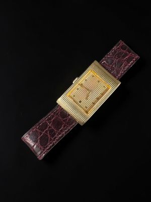 a gold watch on a black surface with a black background