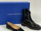 une paire de chaussures en cuir noir avec des lacets cloutés et une boîte bleue