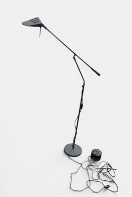 une lampe noire posée par terre à côté d'un casque audio