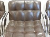 three brown leather chairs with chrome legs in a white room