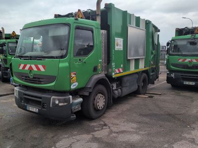 several green garbage trucks parked in a parking lot next to each other