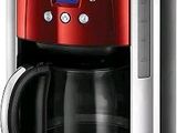 La cafetière est rouge et argentée, avec une carafe en verre.