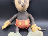 disney mickey mouse plush toy sitting on a black surface