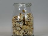 a glass jar filled with nuts on a white surface