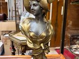 statue en bronze représentant une femme coiffée d'un chapeau, posée sur une table