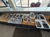 Plusieurs plateaux remplis d'ustensiles sont posés sur une table devant une fenêtre.