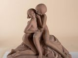 sculpture of two women sitting on a rock with a ball in their hands
