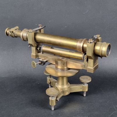an antique brass telescope on a tripod stand on a grey background
