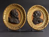 pair of carved bronze portraits of two men in oval frames