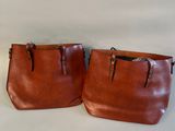 deux porte-monnaie en cuir marron posés sur une table blanche