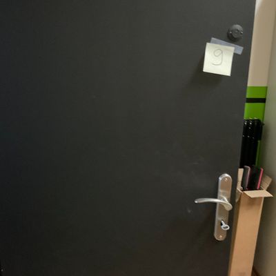une porte noire sur laquelle est accrochée une pancarte, dans une pièce