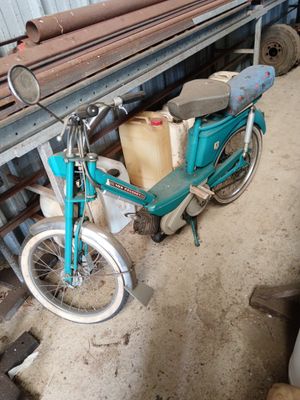 a blue motorcycle parked in a garage with a lot of junk on the floor